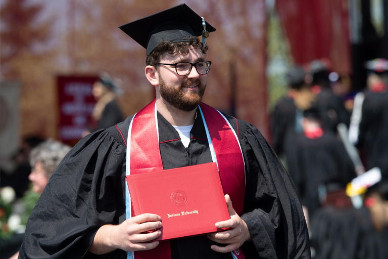 A joyful graduate cradling an IU diploma